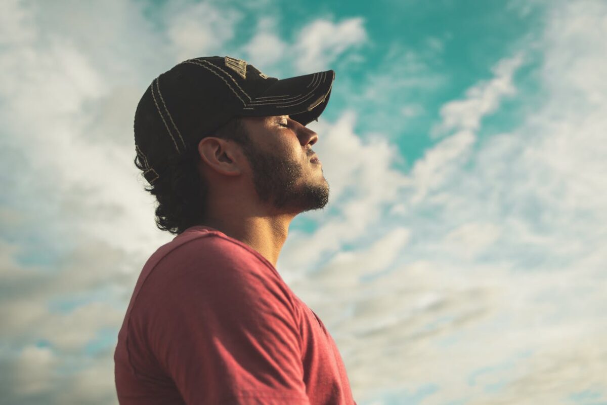 about-img-02 A man enjoys outdoor relaxation and mindfulness beneath a bright, cloudy sky, exuding calm and peace.